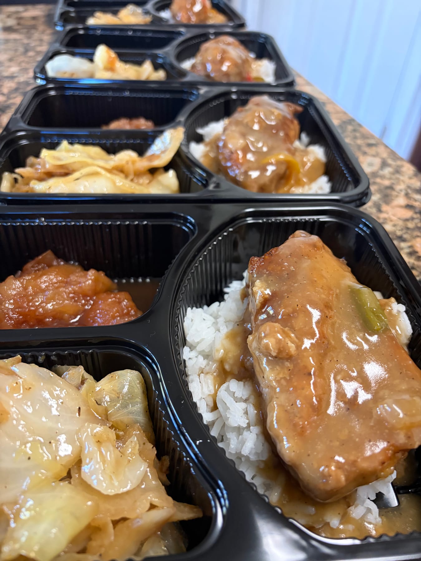 Chicken with gravy, rice, cabbage, and sweet potatoes in meal-prep trays