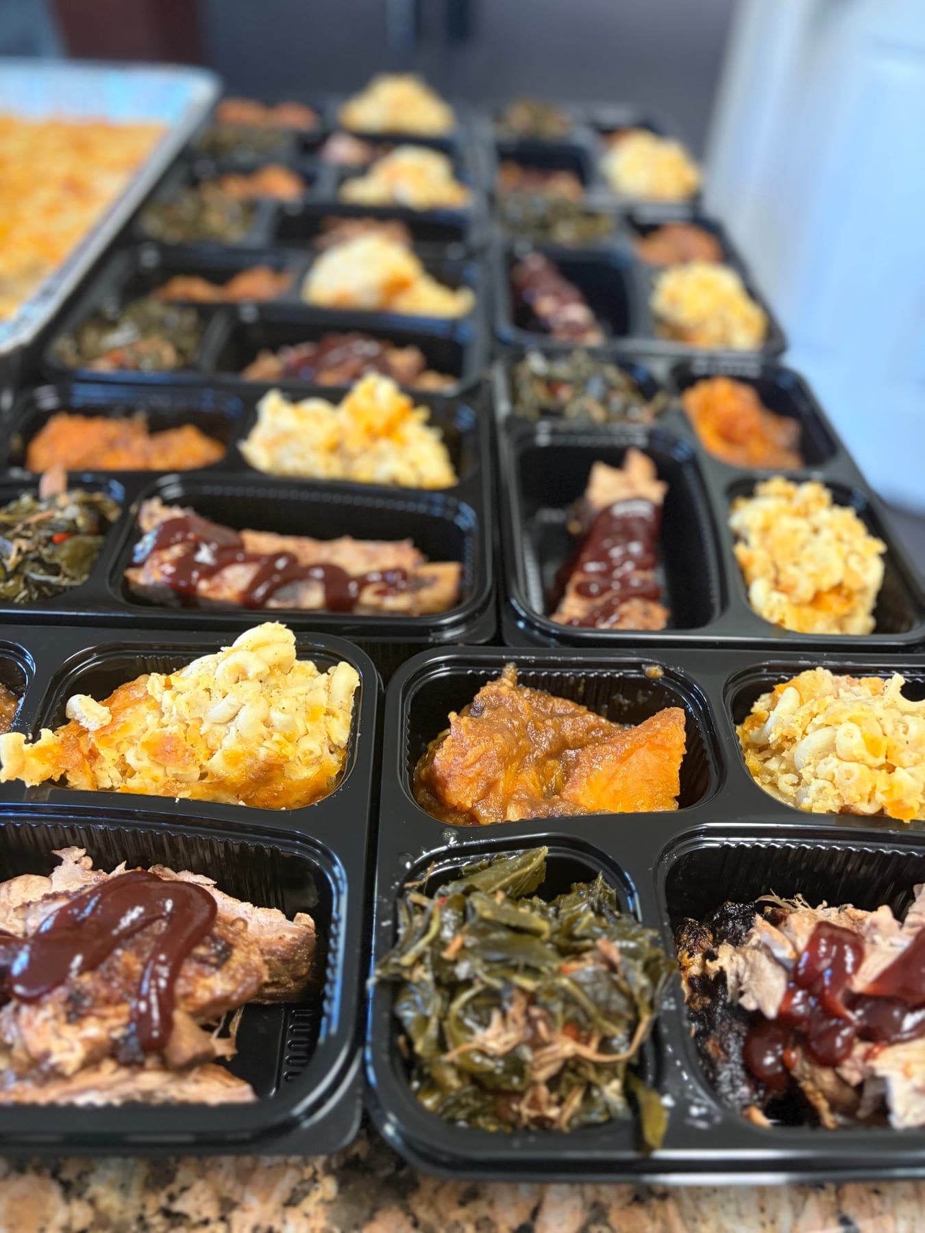 Ribs, macaroni and cheese, greens, and sweet potatoes in meal-prep trays